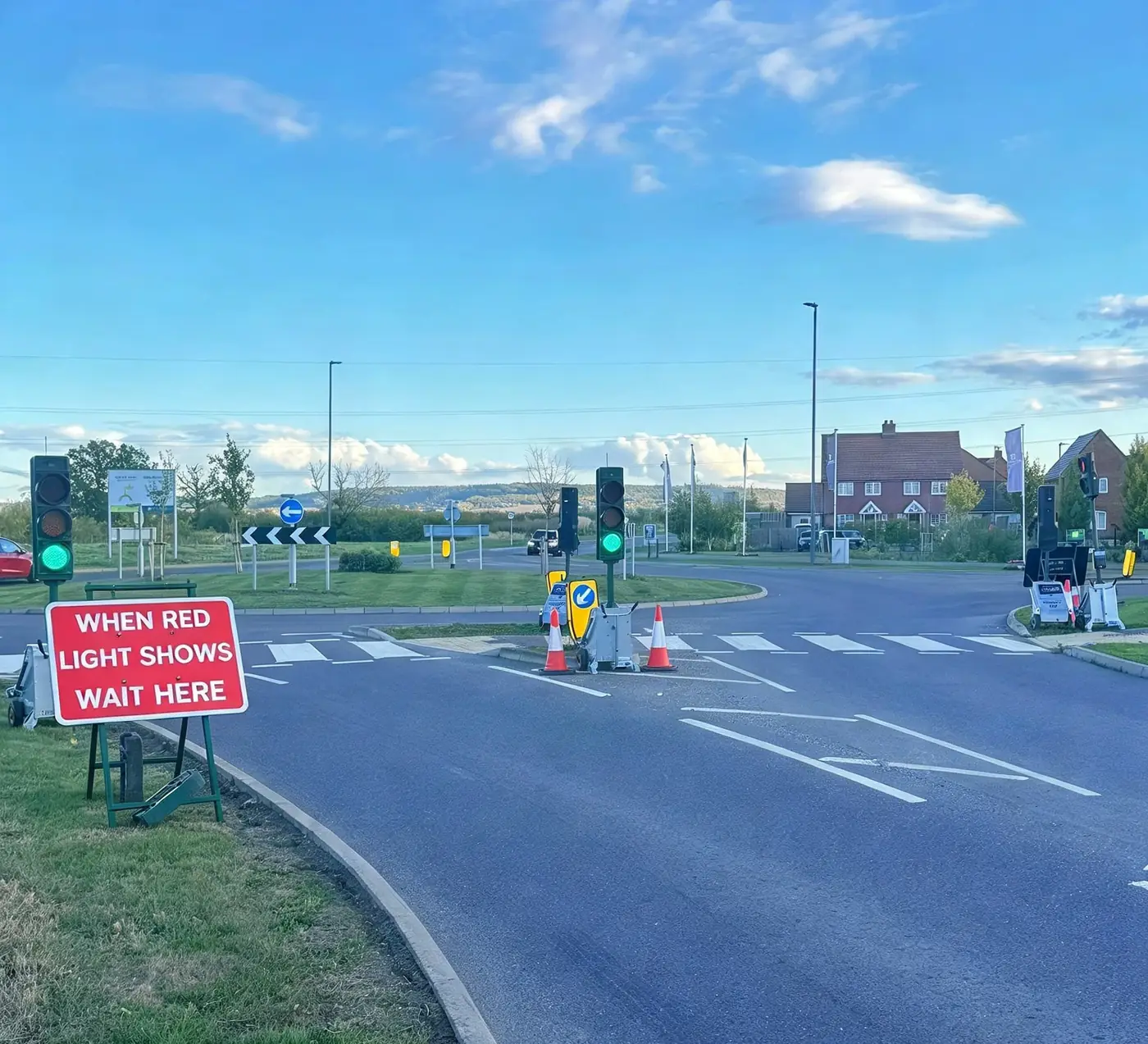 Portable traffic signals and a When Red Light Shows Wait Here sign at a roundabout